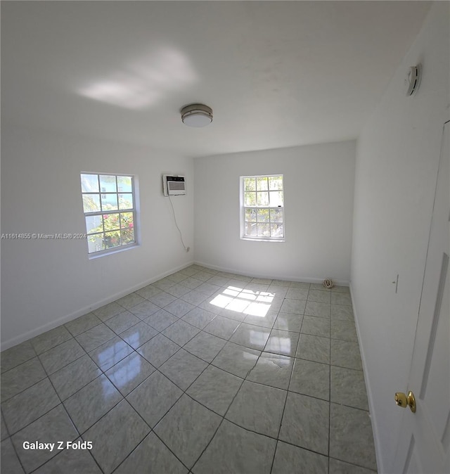 empty room featuring an AC wall unit and light tile patterned floors