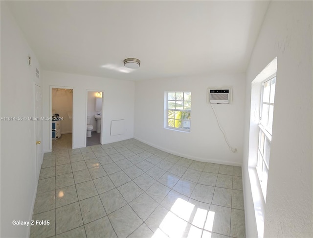 empty room with lofted ceiling, light tile patterned floors, and a wall mounted air conditioner