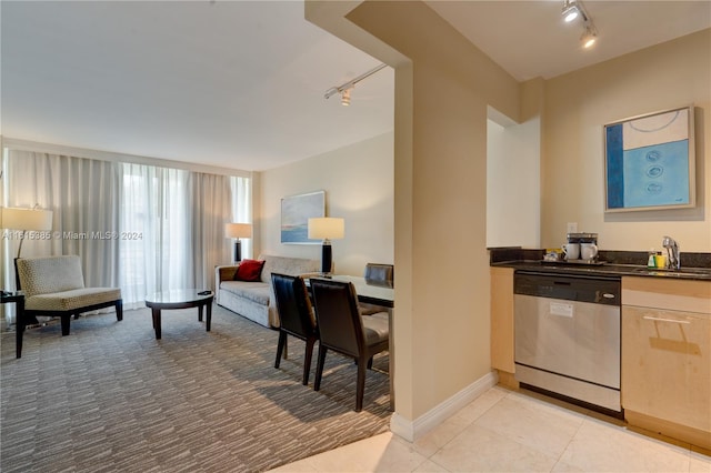 interior space with light tile patterned flooring, track lighting, sink, and stainless steel dishwasher