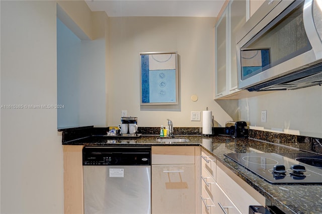 kitchen with sink, dark stone countertops, and stainless steel appliances