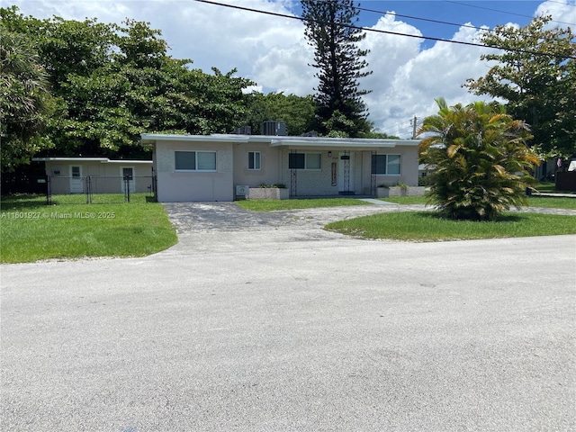 view of front of property with a front yard, cooling unit, stucco siding, fence, and gravel driveway