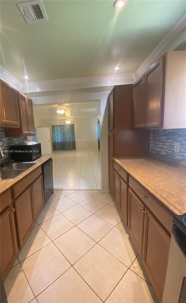 kitchen featuring backsplash, a sink, light tile patterned floors, black dishwasher, and visible vents