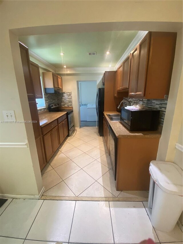 kitchen with independent washer and dryer, black appliances, tasteful backsplash, and light tile floors