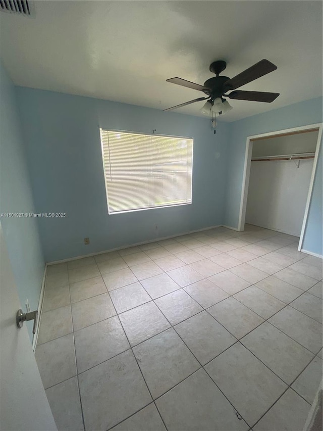 unfurnished bedroom with a closet, visible vents, baseboards, ceiling fan, and tile patterned floors