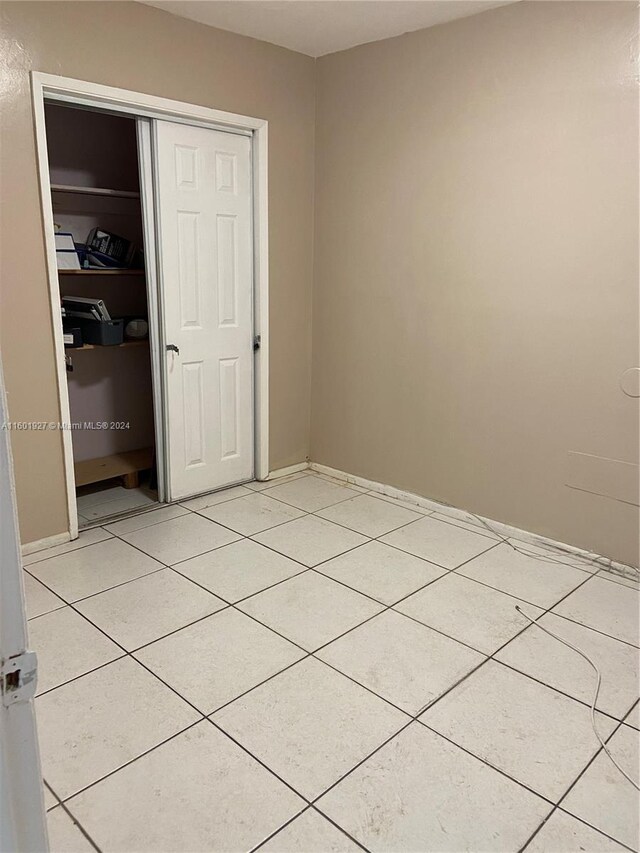 unfurnished bedroom featuring a closet and light tile floors