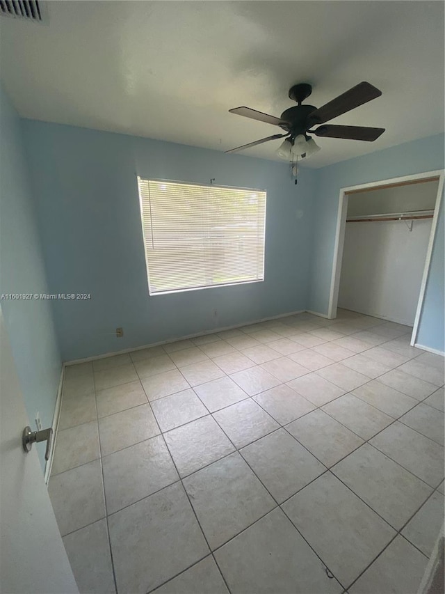 unfurnished bedroom featuring a closet, light tile flooring, and ceiling fan