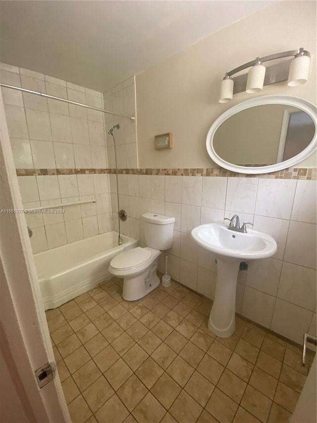 bathroom with tile walls, tasteful backsplash, toilet, tile flooring, and tiled shower / bath