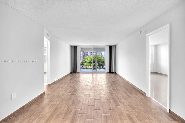 spare room with light hardwood / wood-style floors and a textured ceiling