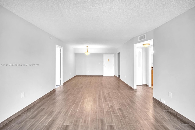 unfurnished room featuring a textured ceiling and dark hardwood / wood-style flooring