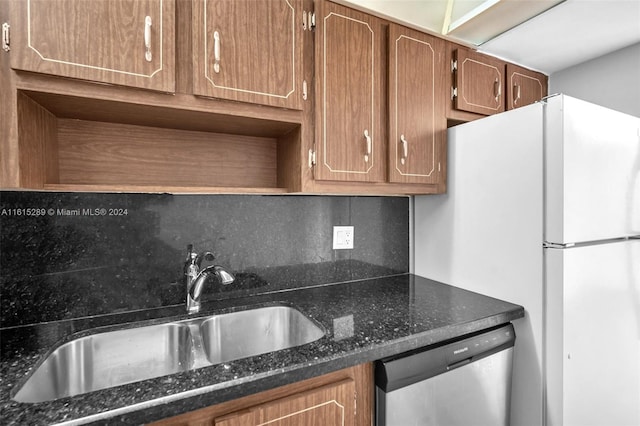 kitchen featuring tasteful backsplash, sink, dark stone counters, and stainless steel appliances