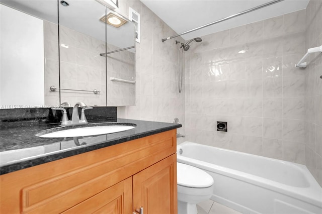 full bathroom featuring vanity, tile patterned floors, tiled shower / bath, toilet, and tile walls