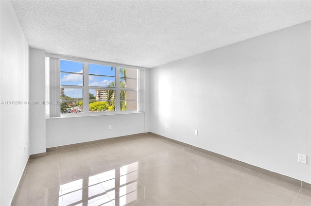 unfurnished room with light tile patterned floors and a textured ceiling