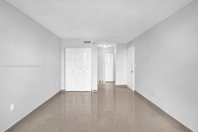 tiled empty room with a textured ceiling