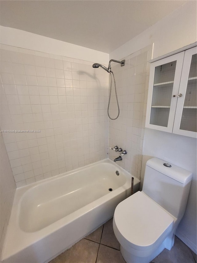 bathroom featuring tiled shower / bath, tile flooring, and toilet