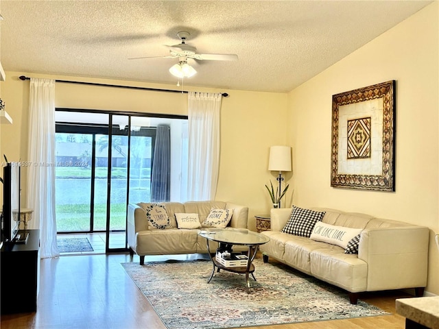 living room with a textured ceiling, ceiling fan, vaulted ceiling, and hardwood / wood-style floors