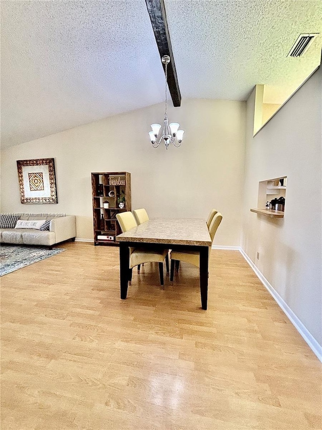 dining area with light wood-type flooring, a chandelier, a textured ceiling, and beam ceiling