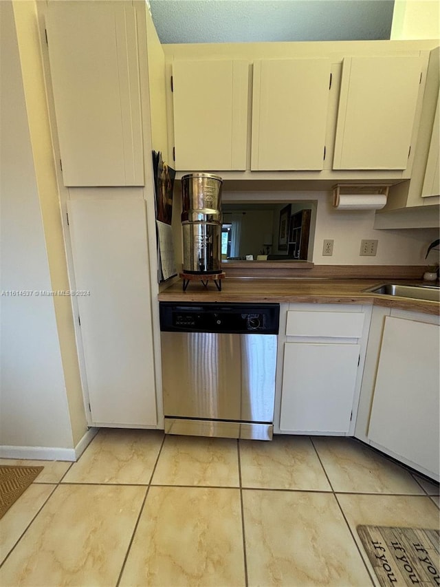 kitchen featuring light tile patterned floors, white cabinets, stainless steel dishwasher, and sink