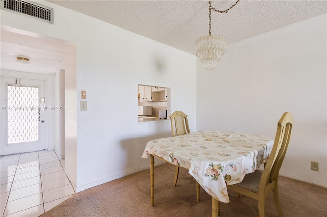 tiled dining room featuring a chandelier and a textured ceiling