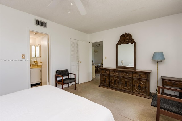 carpeted bedroom featuring a closet, ensuite bathroom, and ceiling fan