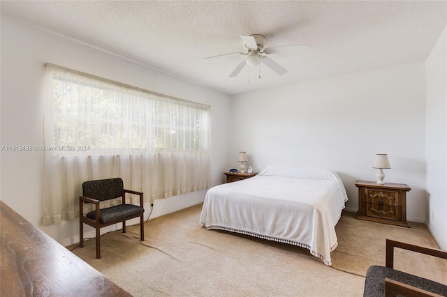 bedroom featuring a textured ceiling, ceiling fan, and light colored carpet