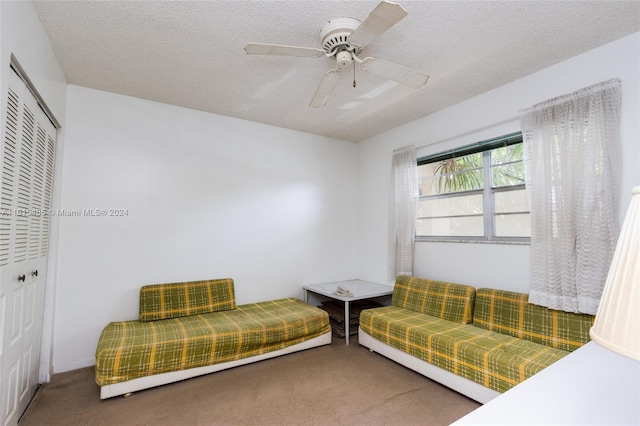 carpeted living room with ceiling fan and a textured ceiling