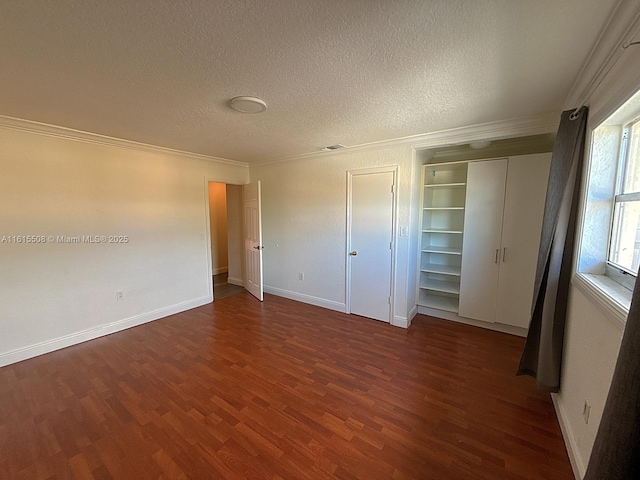 unfurnished bedroom with dark wood-type flooring, ornamental molding, a closet, and a textured ceiling