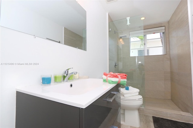 bathroom featuring tiled shower, vanity, and toilet