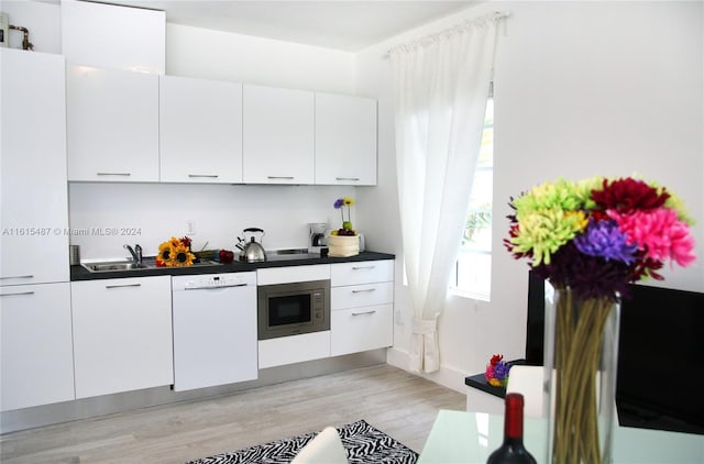 kitchen with light hardwood / wood-style floors, white cabinets, dishwasher, and stainless steel microwave