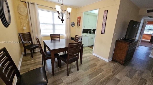 dining room featuring wood-type flooring, an inviting chandelier, and sink