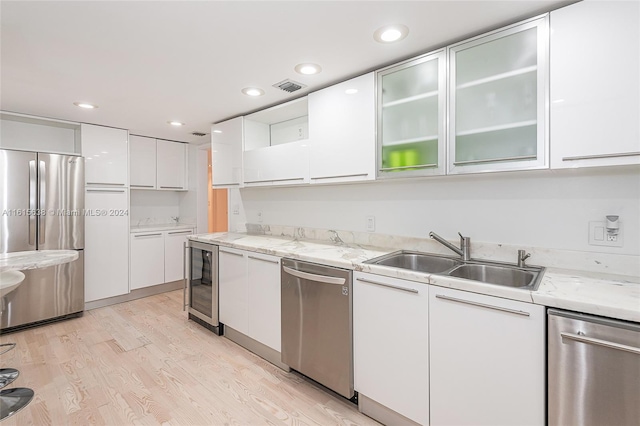 kitchen with sink, wine cooler, light hardwood / wood-style floors, stainless steel appliances, and white cabinets