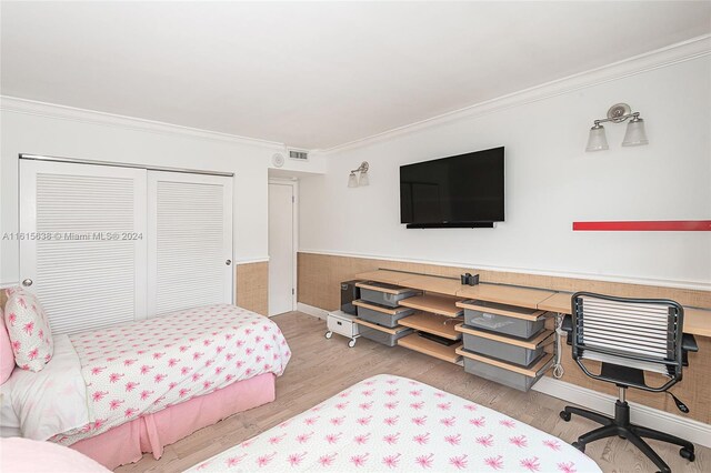 bedroom featuring light hardwood / wood-style flooring, crown molding, and a closet