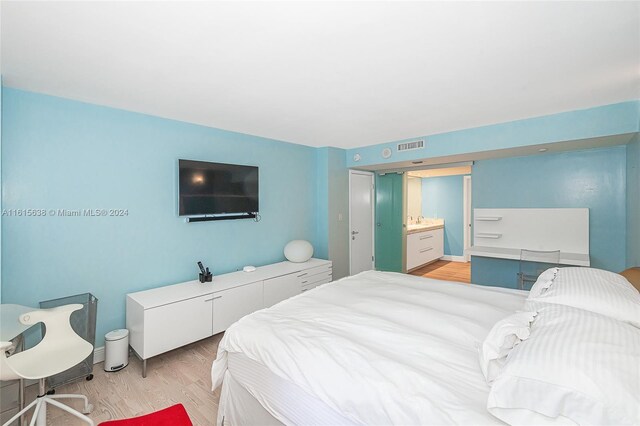 bedroom featuring light hardwood / wood-style flooring and ensuite bathroom