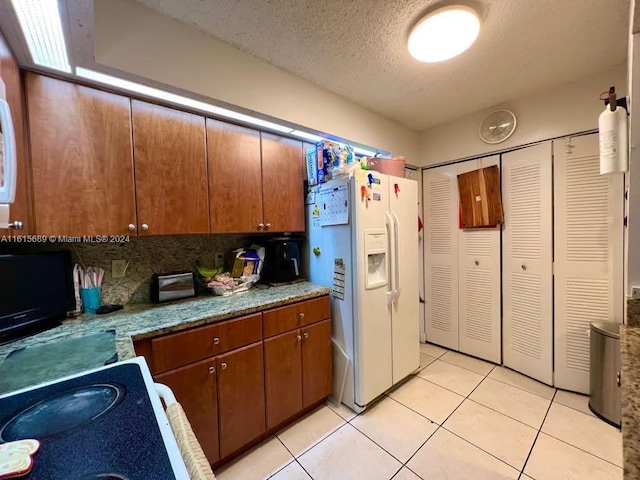 kitchen with white fridge with ice dispenser, light tile patterned floors, a textured ceiling, and tasteful backsplash