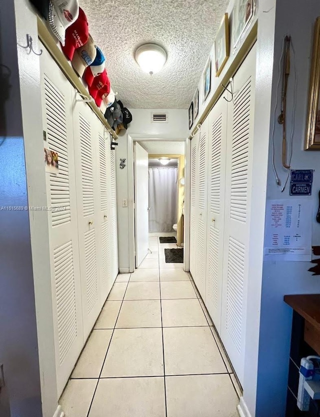 hall featuring a textured ceiling and light tile patterned floors