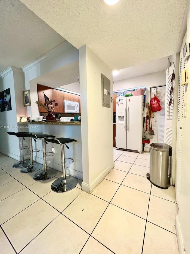 kitchen featuring electric panel, kitchen peninsula, white appliances, a textured ceiling, and light tile patterned floors