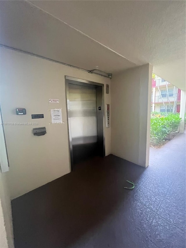 hall featuring elevator and concrete floors