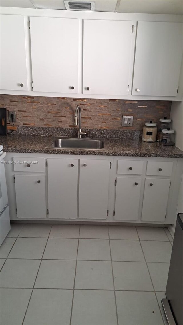 kitchen featuring light tile patterned flooring, sink, decorative backsplash, and white cabinets