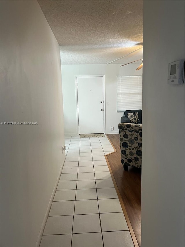 hall featuring a textured ceiling and light tile patterned floors