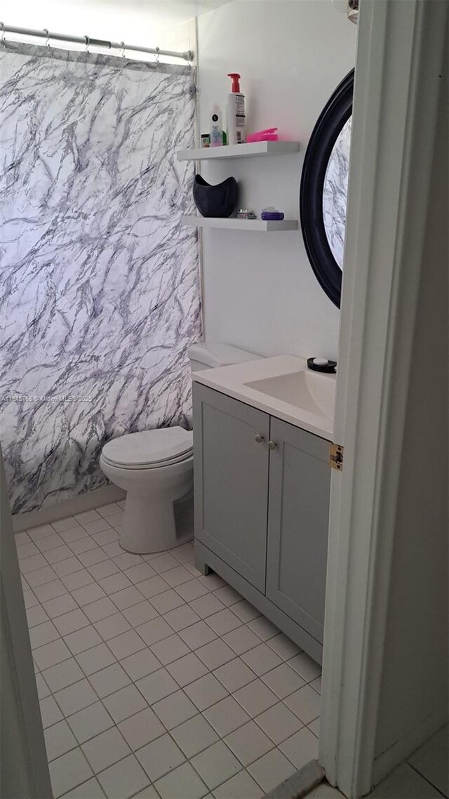 full bathroom featuring vanity, shower / tub combo, tile patterned floors, and toilet