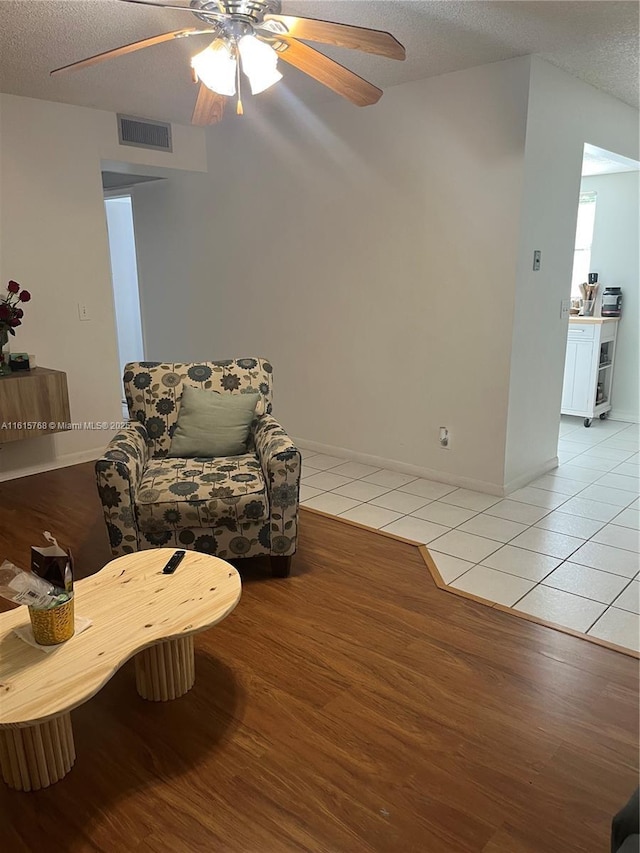 sitting room with ceiling fan, a textured ceiling, and light tile patterned floors