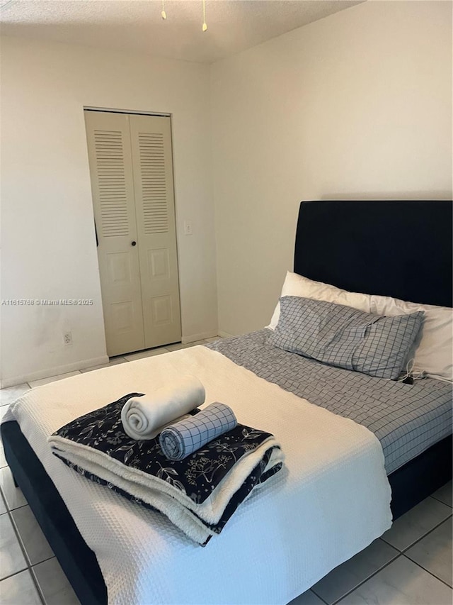 tiled bedroom with a textured ceiling and a closet