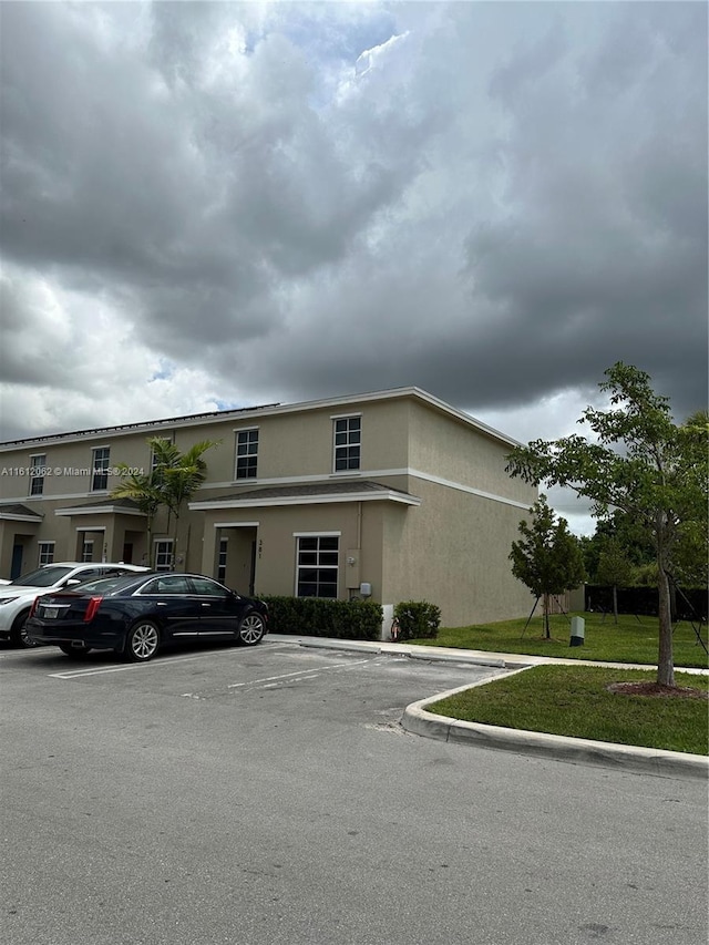 multi unit property featuring stucco siding and uncovered parking