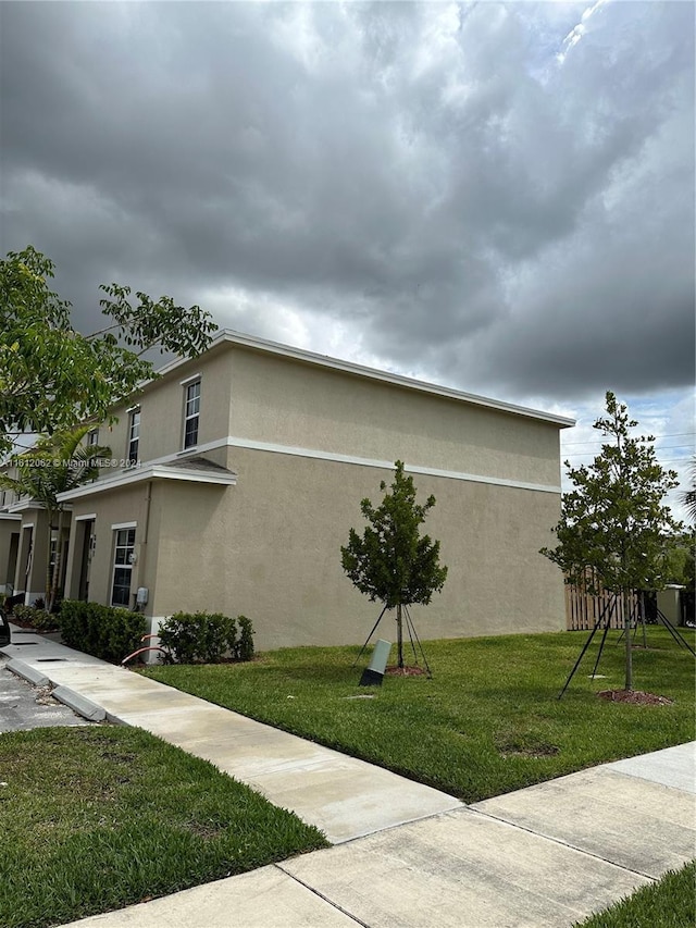 view of home's exterior with stucco siding and a lawn