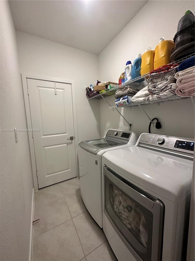 washroom featuring washer and dryer, laundry area, and light tile patterned flooring