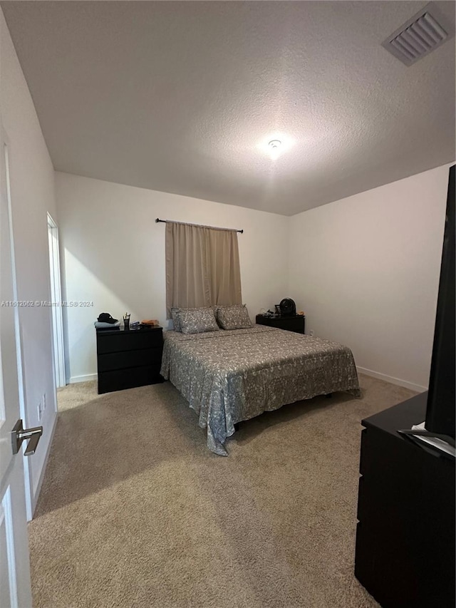 carpeted bedroom featuring visible vents, a textured ceiling, and baseboards