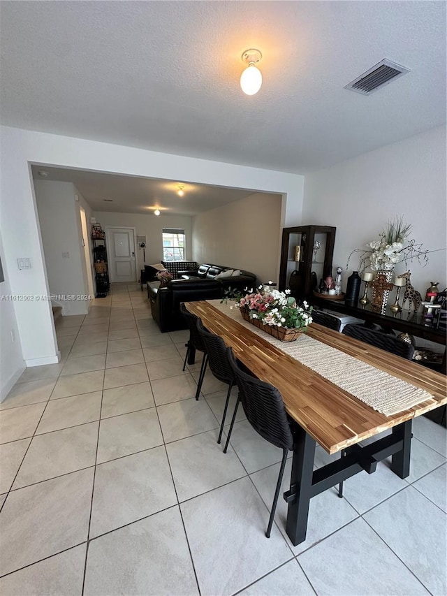 dining area with light tile patterned floors, visible vents, and a textured ceiling