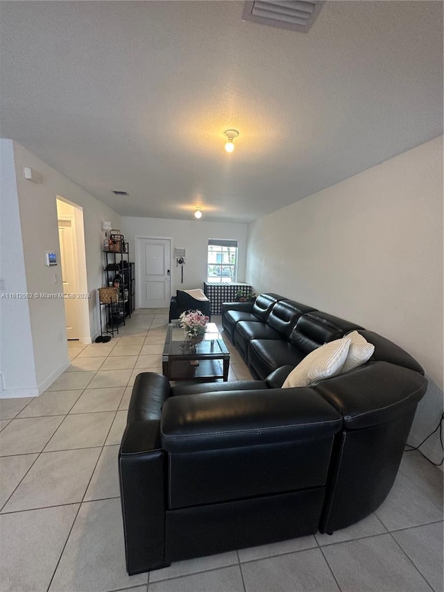 living area with light tile patterned flooring, visible vents, and a textured ceiling