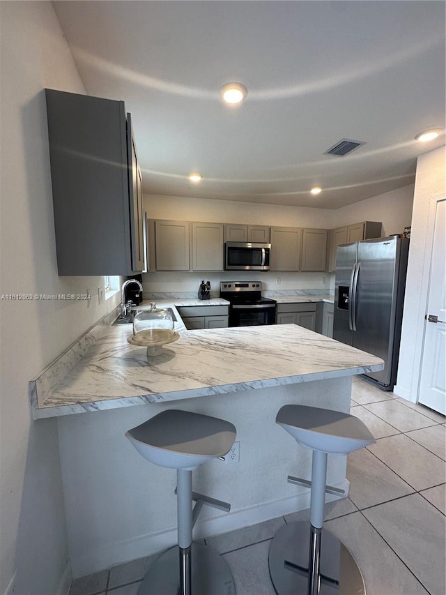 kitchen featuring visible vents, gray cabinets, a sink, appliances with stainless steel finishes, and light countertops