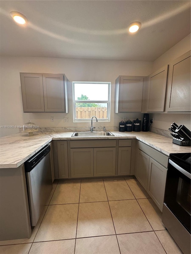 kitchen with light countertops, gray cabinets, stainless steel appliances, and a sink