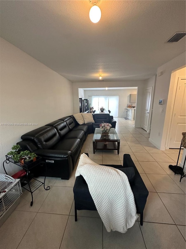 living area with light tile patterned floors, visible vents, and a textured ceiling